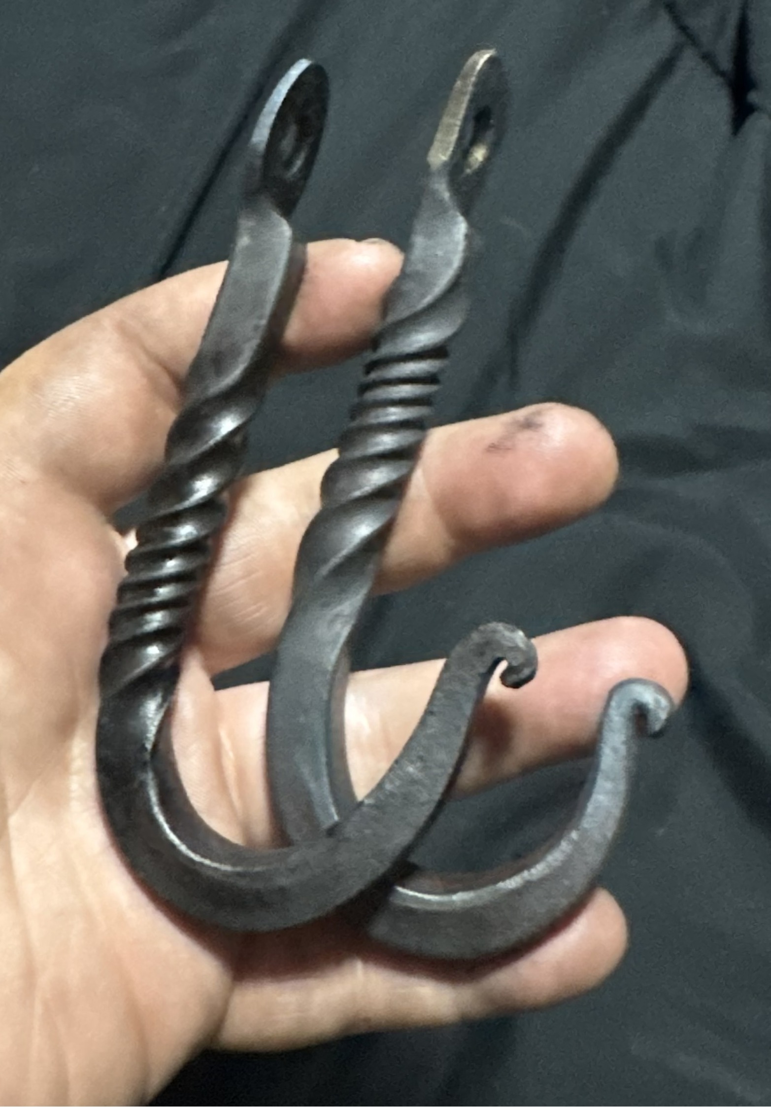 Finished hand-forged hooks held in hand