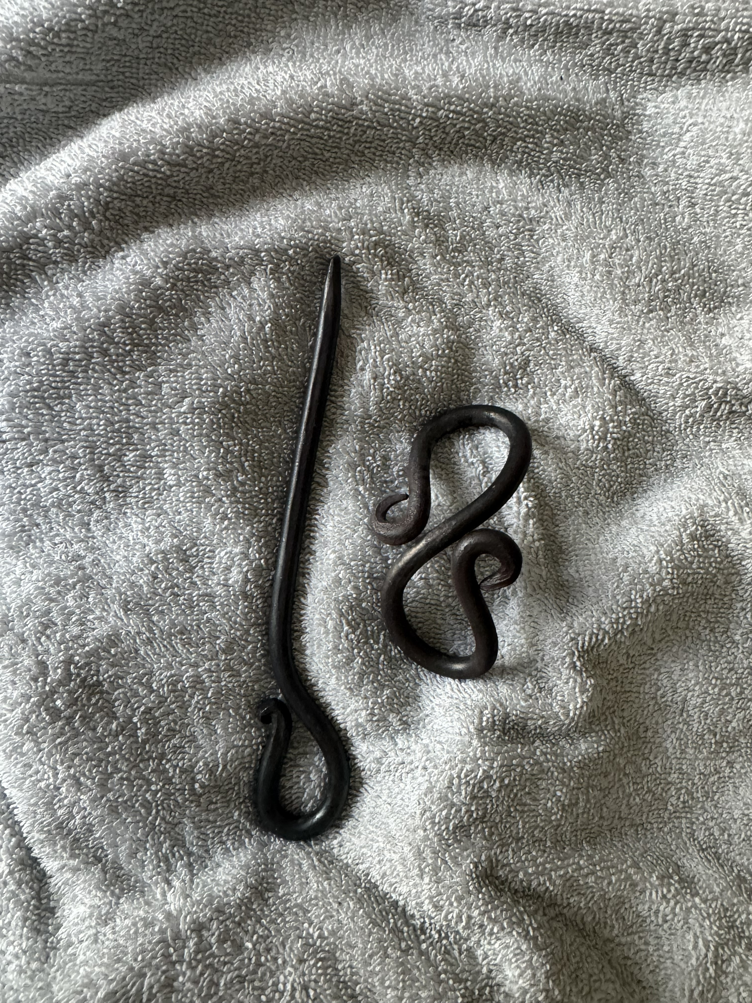 Small forged hook and scroll pieces on a towel